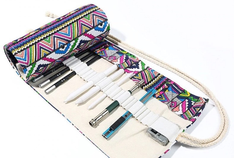 May include: A white canvas roll-up pencil case with a colorful geometric pattern. The case is open and has a variety of pencils, pens, and a utility knife inside.
