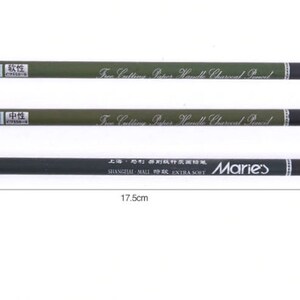 Pu&ograve; includere: Tre matite di carbone con fusti verdi e punte nere. Le matite sono etichettate "Free Cutting Paper Handle Charcoal Pencil" e "SHANGHAI MALI  EXTRA SOFT" con il marchio "Marie's". Le matite hanno un diametro di 0,7 cm e una lunghezza di 17,5 cm.