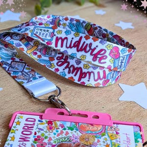 May include: A white fabric lanyard featuring a colorful pattern of medical icons, flowers, and the word midwife in pink script, attached to a bright pink plastic ID badge holder with a metal swivel hook and a clear display window.