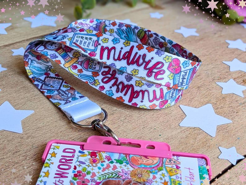 May include: A white fabric lanyard featuring a colorful pattern of medical icons, flowers, and the word midwife in pink script, attached to a bright pink plastic ID badge holder with a metal swivel hook and a clear display window.