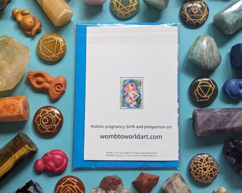May include: A blue card with a white background and a colorful illustration of a woman with a flower crown. The text on the card reads "Holistic pregnancy, birth and postpartum art wombtoworldart.com".