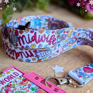 May include: A white fabric lanyard featuring a colorful repeating pattern of medical icons, flowers, and the word midwife in pink script. The lanyard includes a silver metal lobster clasp attached to a bright pink plastic ID badge holder.