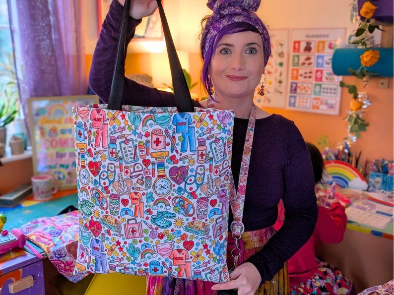 May include: A white tote bag with a colorful print of medical symbols, including hearts, bandages, stethoscopes, and pills. The bag has black handles and a rainbow-colored strap.