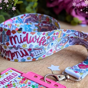 May include: A white fabric lanyard featuring a colorful repeating pattern of medical icons, flowers, and the word midwife in pink script. The lanyard includes a silver metal lobster clasp attached to a bright pink plastic badge holder.