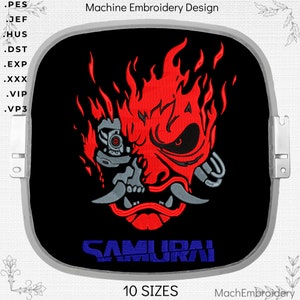 Może przedstawiać: Wzór do haftu maszynowego przedstawiający czerwoną i szarą maskę samuraja z płomieniami na czarnym tle. Tekst "SAMURAI" jest wyświetlany na niebiesko pod maską. Wzór jest dostępny w 10 rozmiarach.