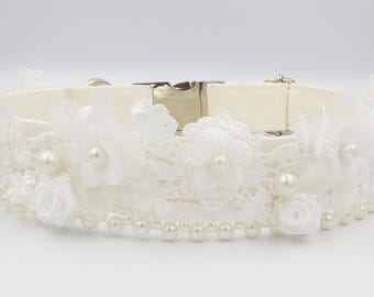 May include: Ivory dog collar with white lace, pearl accents, and floral embellishments. The collar features a silver metal clasp and is adorned with delicate white flowers and faux pearls, creating an elegant look.