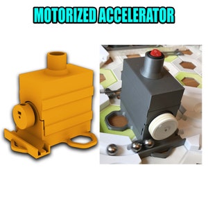 Pu&ograve; includere: Un acceleratore di biglie motorizzato con una base gialla e una parte superiore grigia. L'acceleratore ha un interruttore sulla parte superiore e una ruota bianca sul lato. L'acceleratore fa parte di una pista di biglie.