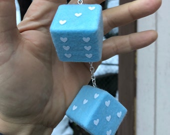 May include: A blue felt dice charm with white hearts on each side, hanging from a silver chain.