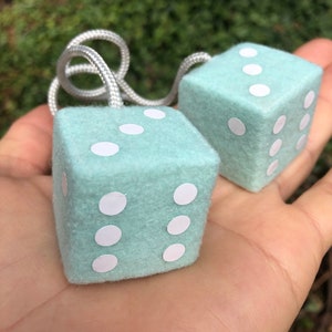 May include: Two fuzzy, light blue dice with white dots. The dice are attached to a white string.