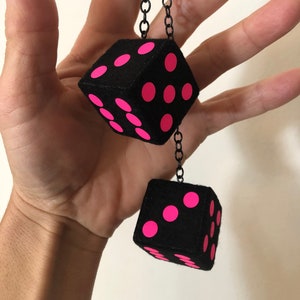 May include: A pair of black fuzzy dice with pink dots hanging from a black chain.