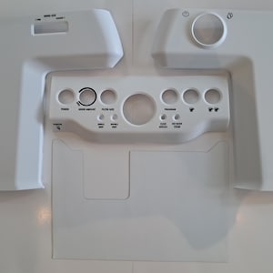 May include: White appliance components with cutouts and text labels. Sections are labelled for grind size, filter size, and program settings. The design includes circular openings and a rectangular cutout.