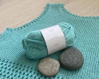 Puede incluir: Un top de crochet azul turquesa con un ovillo de hilo azul turquesa y la etiqueta "Sandnes Garn LINE" en él. Dos piedras grises están delante del hilo.