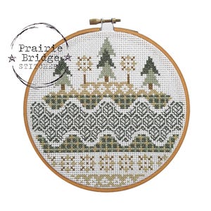 Può includere: Un cerchio da ricamo a punto croce con un disegno di una scena di foresta. Il disegno presenta alberi verdi, colline marroni e uno sfondo bianco. Il cerchio è in legno e ha una finitura marrone.