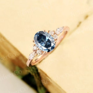 May include: A rose gold engagement ring with a large oval blue gemstone surrounded by smaller diamonds. The ring has a delicate, floral design.