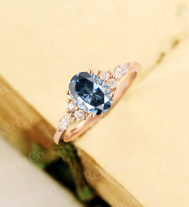 May include: A rose gold engagement ring with a large oval blue gemstone surrounded by smaller diamonds. The ring has a delicate, floral design.