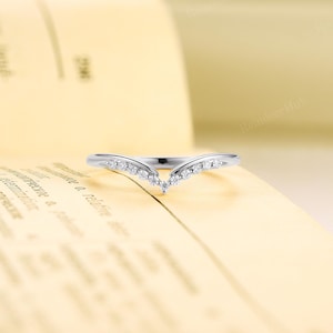 K&ouml;nnte beinhalten: Ein zarter Silberring mit einem V-f&ouml;rmigen Band, das mit kleinen, funkelnden Diamanten besetzt ist.