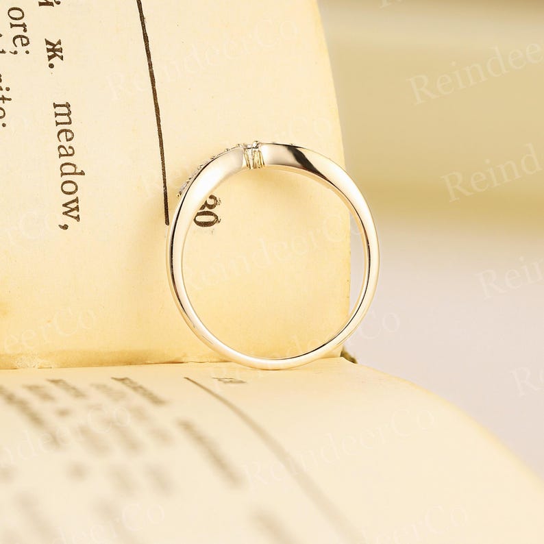 K&ouml;nnte beinhalten: Ein zarter Ring aus Wei&szlig;gold mit einem kleinen Diamanten in der Mitte. Der Ring liegt auf einer cremefarbenen Oberfl&auml;che.