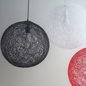 Może przedstawiać: Trzy wiszące lampy w kształcie lampionu wykonane z plecionego sznurka. Lampy są czarne, białe i czerwone.
