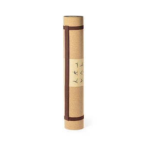 May include: Rolled cork yoga mat with a brown strap and a label featuring yoga poses. The mat is a light tan color and appears to be made of natural cork material. The strap is wrapped around the mat to keep it rolled up.