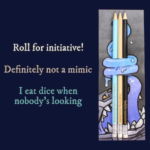 Può includere: L'immagine presenta tre matite: azzurra, beige e nera, tenute da un mostro blu dei cartoni animati. Le matite riportano le scritte "Roll for initiative!" e "Definitely not a mimic". L'immagine include anche il testo "I eat dice when nobody's looking".