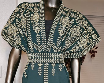 May include: A dark green, open-front dress with intricate gold embroidery. The dress features a V-neck, short sleeves, and a detailed embroidered pattern along the edges and waist. The dress is displayed on a mannequin.