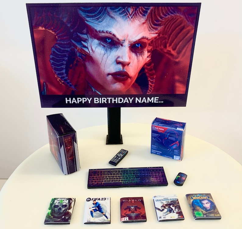 K&ouml;nnte beinhalten: Ein Miniatur-Gaming-Setup mit einem schwarzen Computer-Tower, einer Tastatur und einer Fernbedienung. Der Monitor zeigt einen Videospielcharakter mit dem Text "Happy Birthday Name..." auf dem Bildschirm. Es gibt auch Miniatur-Spielboxen und ein Headset.