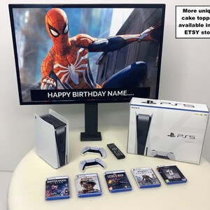 K&ouml;nnte beinhalten: Eine wei&szlig;e PlayStation 5 Konsole mit einem schwarzen Controller und einer Spielscheibe. Die Konsole steht auf einem wei&szlig;en Tisch mit einem wei&szlig;en und schwarzen Fernsehbildschirm im Hintergrund. Der Fernsehbildschirm zeigt eine Videospielfigur, Spider-Man, in einem roten und blauen Anzug. Der Text "HAPPY BIRTHDAY NAME..." wird auf dem Bildschirm angezeigt. Auf dem Tisch liegen mehrere Spielscheiben, darunter "WATCH DOGS LEGION", "SPIDER-MAN" und "ASSASSIN'S VALHALLA".