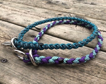 May include: Two braided dog collars, one teal and black, the other purple and green with a white pattern. Both collars have silver metal clasps.