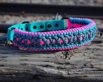 Puede incluir: Un collar de perro de paracord rosa y turquesa con una hebilla negra.