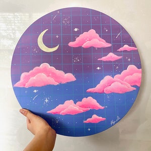 Könnte beinhalten: Ein rundes, violettes und blaues Leinwandbild mit einem Gittermuster. Das Bild zeigt rosa Wolken, einen Halbmond und weiße Sterne. Die Unterschrift des Künstlers befindet sich in der rechten unteren Ecke.