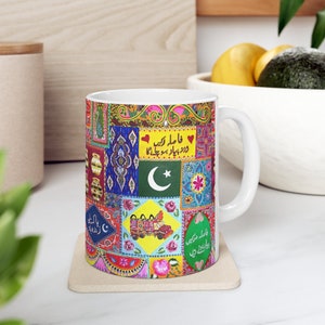May include: A white ceramic mug with a colorful design featuring a Pakistani flag, truck, and traditional patterns. The text on the mug reads "Ya Allah rekh", "Wazirpur", and "Allah Rakhey".