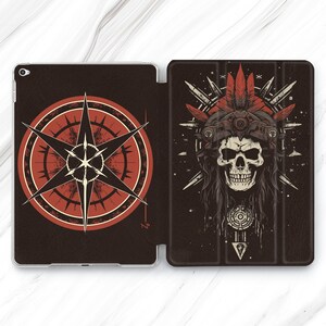 Op de afbeelding: Een zwarte en rode iPad-hoes met een kompasontwerp aan de voorkant en een schedel met een hoofdtooi aan de achterkant.