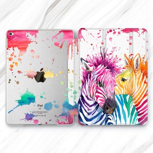 May include: A white iPad case with a watercolor design of two zebras with colorful stripes. The background is a white with colorful paint splatters. The case has a flap that folds over the front of the iPad.
