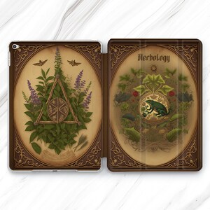 May include: A brown leather iPad case with a gold-coloured design. The front cover features a botanical illustration with a triangle and a frog. The back cover has the text "Herbology II" in a gold-coloured font.