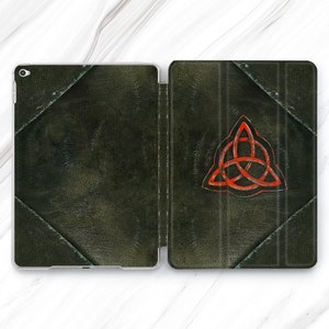Pode incluir: Uma capa de iPad de couro verde com um design de nó celta vermelho. A capa está fechada e tem uma superfície texturizada.