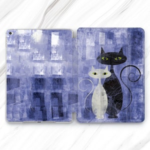 Puede incluir: Una funda para iPad con estampado azul y blanco con una ilustración en blanco y negro de dos gatos. Los gatos están mirando hacia adelante con sus colas enroscadas entre sí.