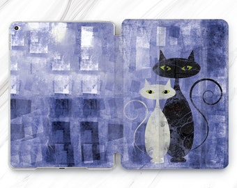 May include: A blue and white patterned iPad case with a black and white illustration of two cats. The cats are facing forward with their tails curled around each other.