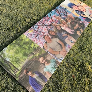 May include: A yoga mat with a collage of family photos printed on it. The photos show a group of people in a park, a family portrait with a cherry blossom tree in the background, and a couple of children.
