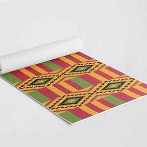 May include: A rolled up yoga mat with a colorful geometric pattern. The pattern features yellow, red, green, and black stripes with diamond shapes.
