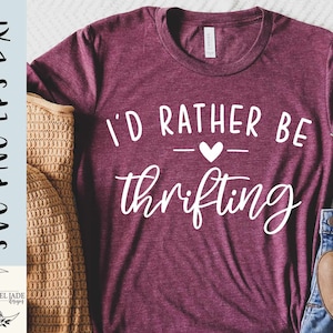 May include: A maroon t-shirt with the text "I'd rather be thrifting" in white with a small white heart between the words.