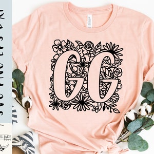 Może przedstawiać: Różowa koszulka z czarnym wzorem kwiatowym z literami "GG" w środku.