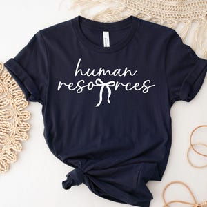 May include: Navy blue t-shirt with the words "human resources" in a white script font. The text is embellished with a bow design. The words "INSTANT ACCESS" and "DIGITAL DOWNLOAD" are printed above and below the main text.