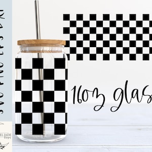 May include: A 16 oz glass with a black and white checkered pattern. The glass is sitting on a wooden surface.