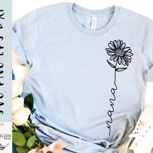 May include: A light blue t-shirt with a black line drawing of a sunflower and the word "mama" written in a script font.