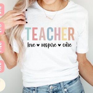 Może przedstawiać: Biała koszulka z napisem "TEACHER" w pastelowych kolorach. Pod słowem "TEACHER" znajdują się słowa "love inspire care" ze znakami serca. Koszulka ma okrągły dekolt.
