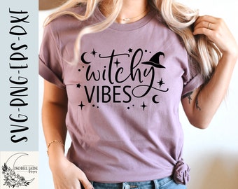 May include: A mauve t-shirt with the words "witchy vibes" in black script, along with a witch hat, stars, and crescent moons. The shirt also has the text "SVG-PNG-EPS-DXF" and the Isobel Jade Designs logo.