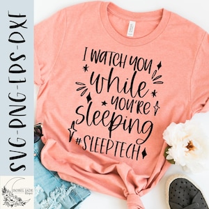May include: A peach-colored t-shirt with the text "I watch you while you're sleeping #SLEEPTECH" in black. The text is surrounded by stars and diamonds.