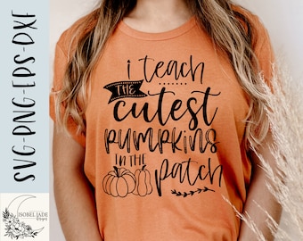May include: Orange t-shirt with black text that reads "I teach the cutest pumpkins in the patch". The text is in a handwritten font. There are two black pumpkins in the bottom left corner of the shirt.
