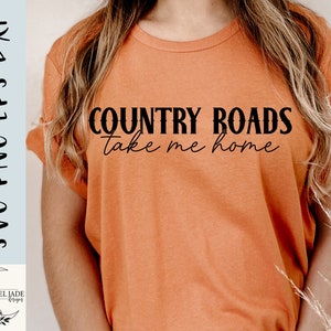 May include: A woman wearing a light orange t-shirt with the text "COUNTRY ROADS take me home" printed in black.
