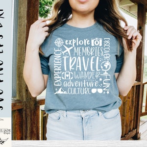 May include: A woman wearing a blue t-shirt with white text that says "Explore Memories Travel Wander Adventure Culture Discover Fun". The text is arranged in a circle around a compass, airplane, suitcase, globe, and sunglasses.